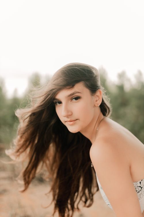 Free A serene portrait of a young woman outdoors with flowing hair. Stock Photo