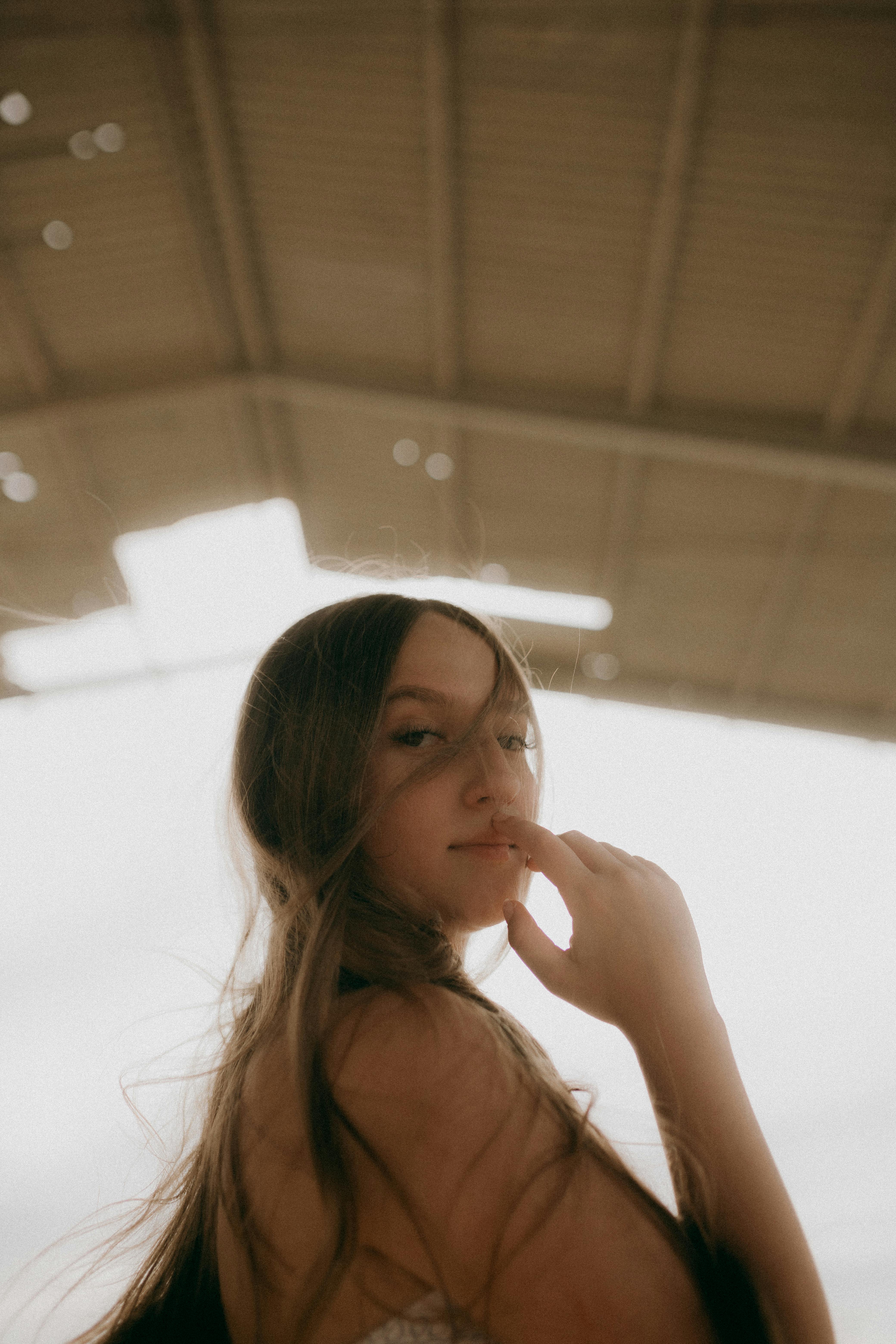 Artistic portrait of a young woman in a warehouse setting, soft light.
