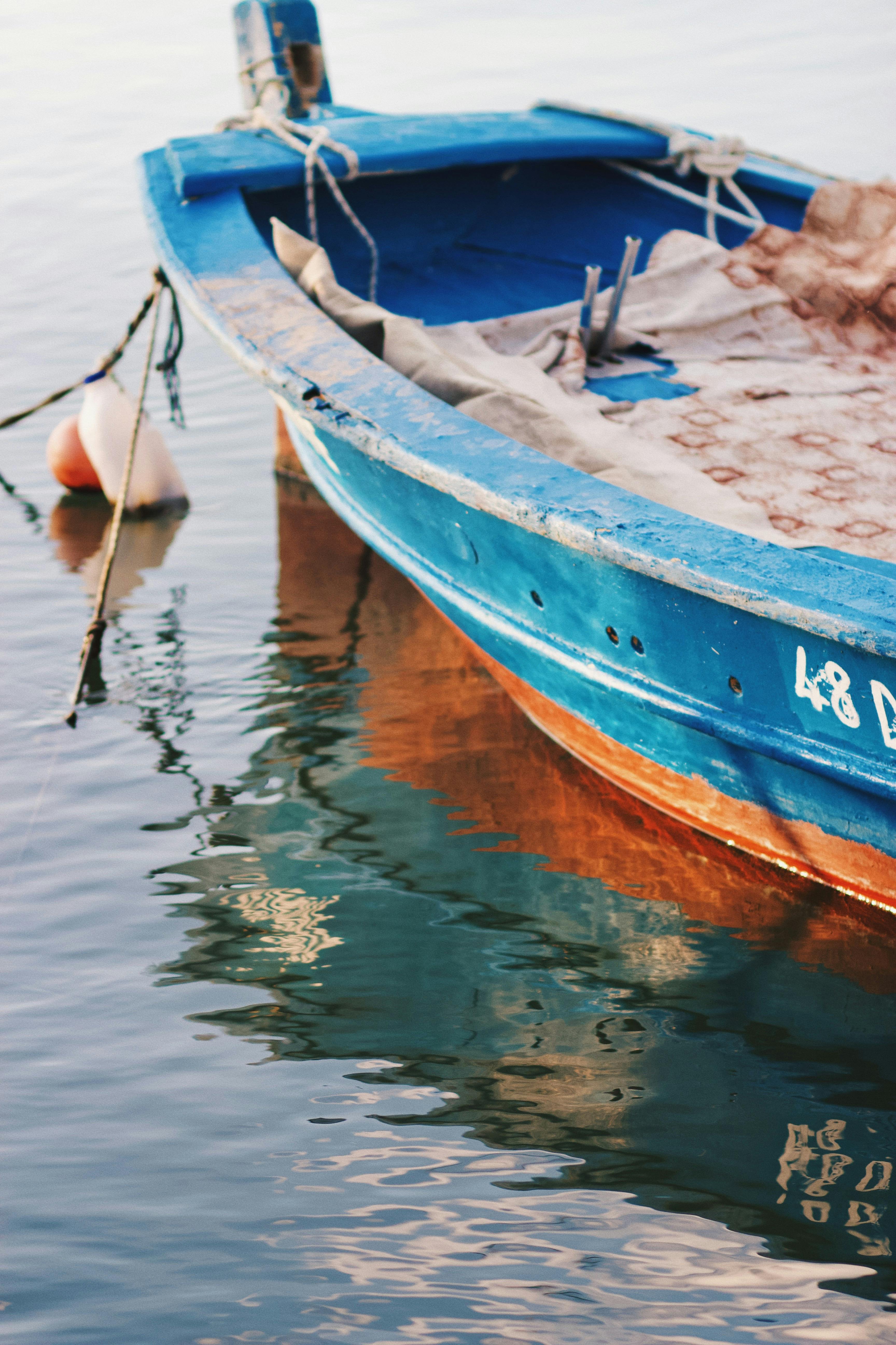 A peaceful scene featuring a blue boat reflected in tranquil water, perfect for travel and nature themes.