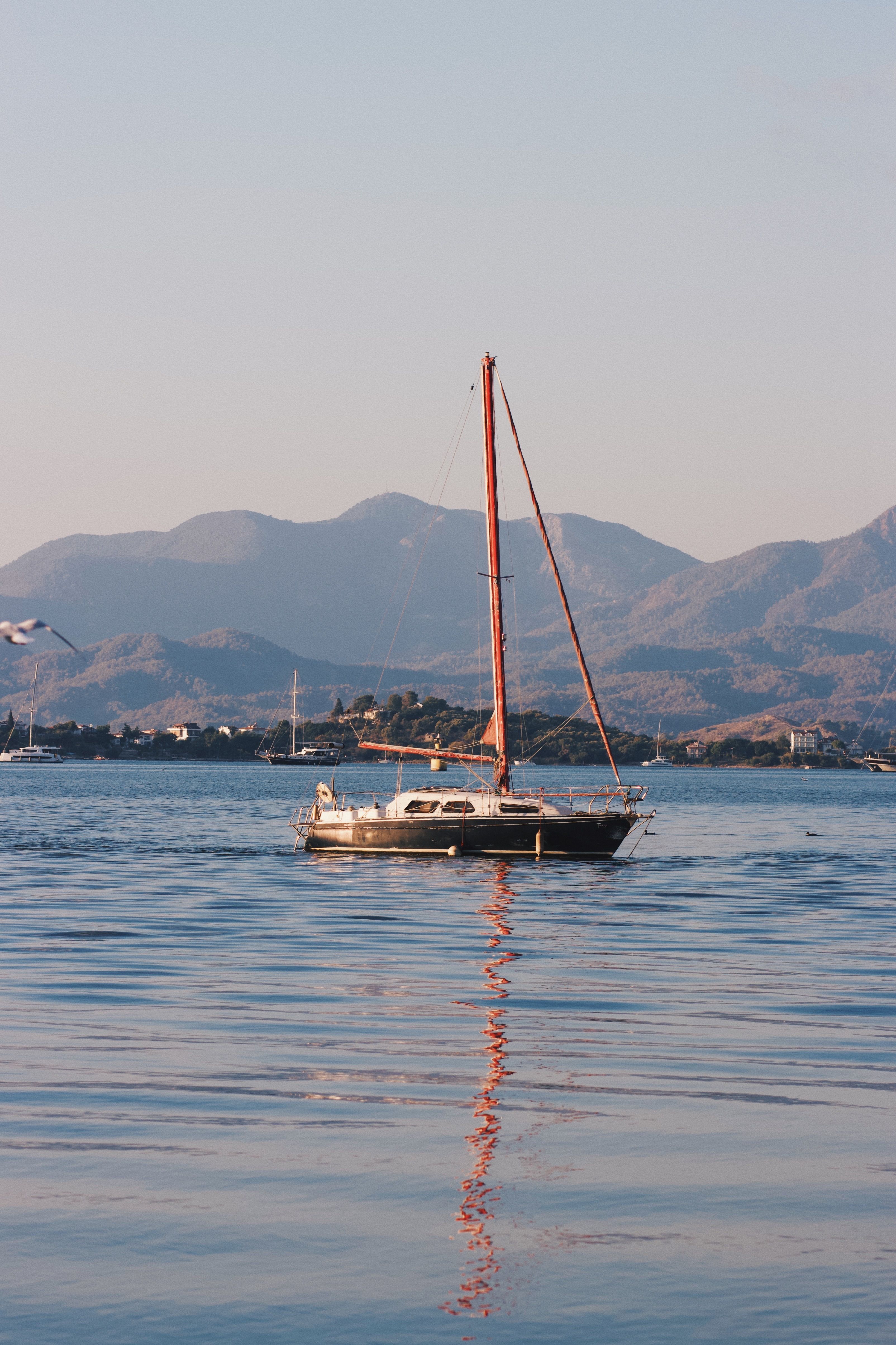Serene Sailboat on Calm Mountain Lake at Sunset · Free Stock Photo