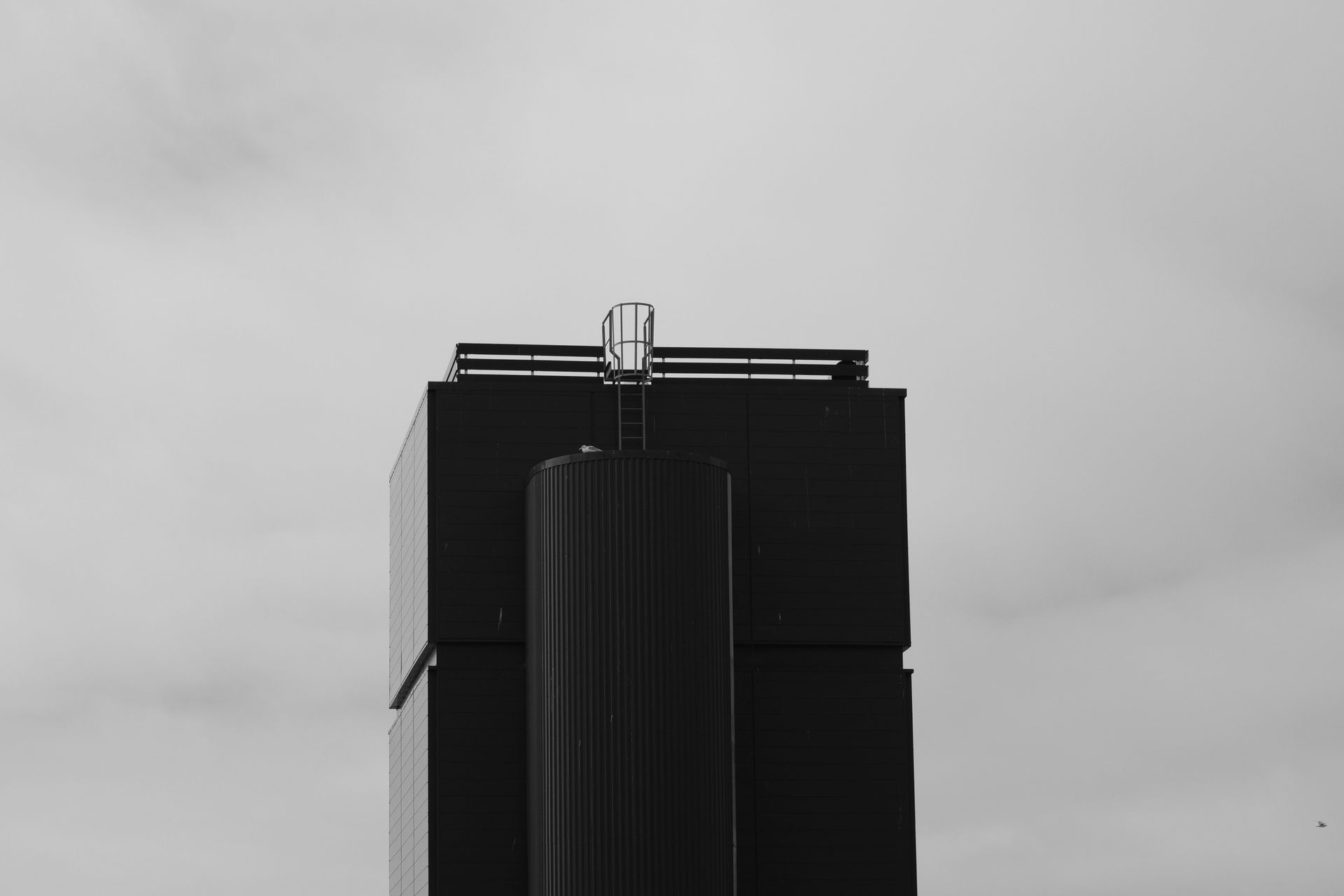 Black and white photo of a modern industrial building under cloudy skies.