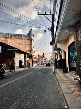 A bustling city street scene captured during sunset with shops and pedestrians adding life to the vibrant urban landscape.