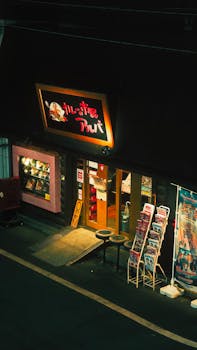 Charming Japanese restaurant at night, illuminated sign and street posters, inviting ambiance.