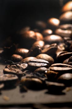 Detailed shot of roasted coffee beans in warm lighting, perfect for coffee lovers' themes.