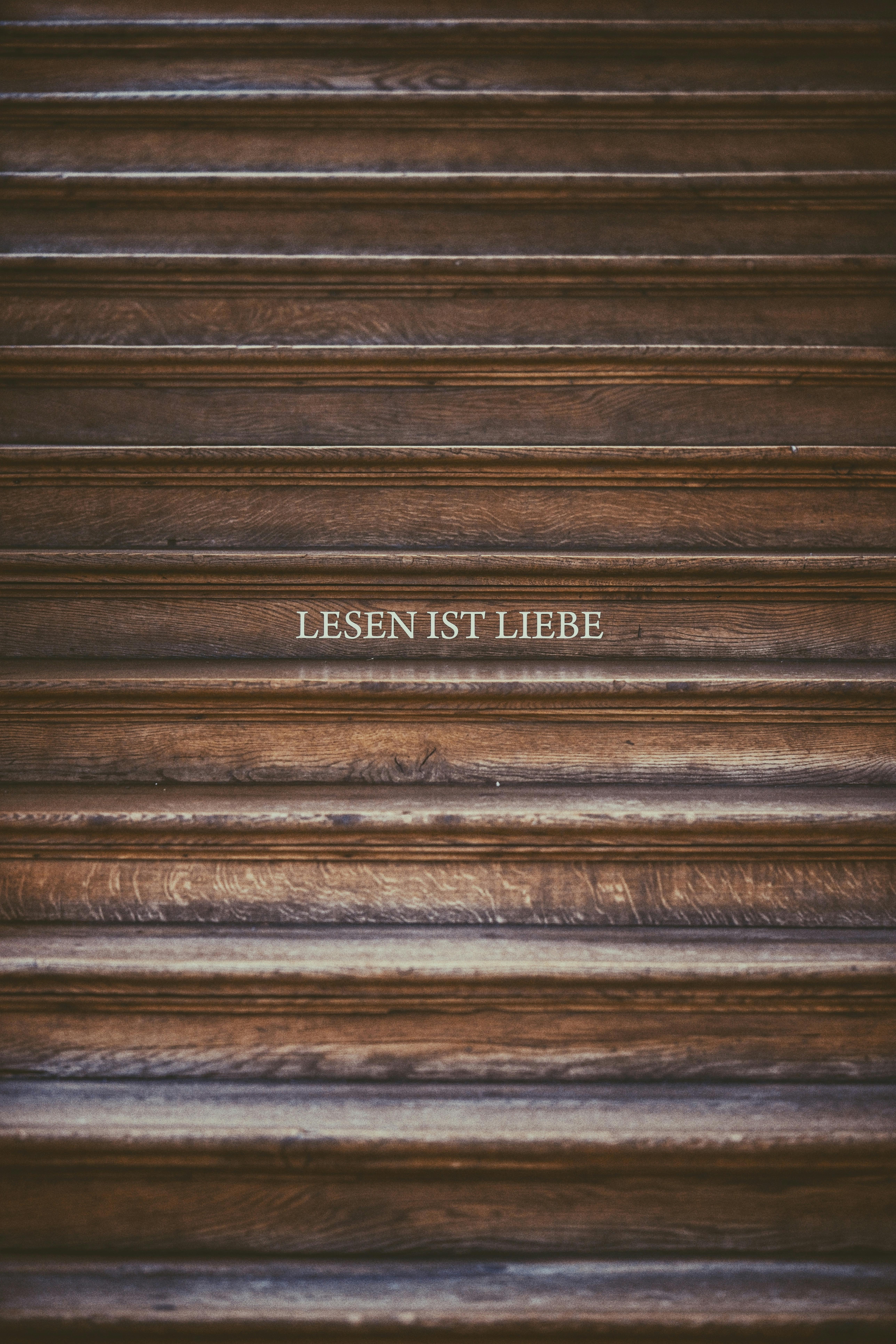 Wooden wall with 'Lesen ist Liebe' text in elegant serif font.