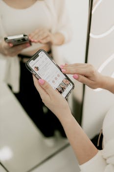 Close-up of a woman using her smartphone in front of a mirror indoors.