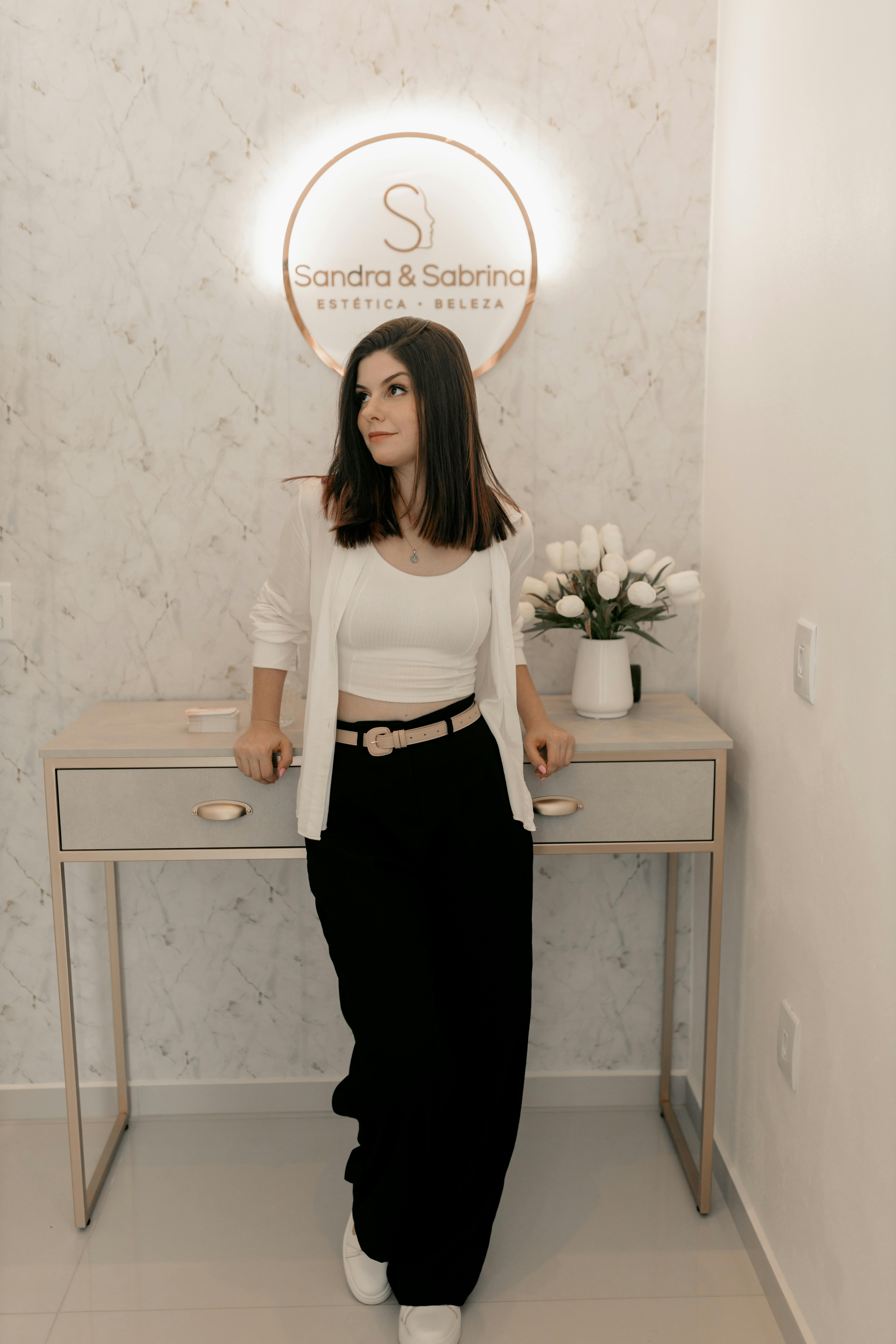 Woman stands elegantly in a chic esthetic salon, exuding modern style and grace.