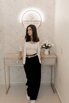Woman stands elegantly in a chic esthetic salon, exuding modern style and grace.