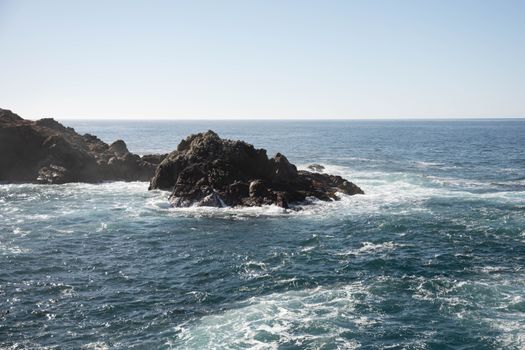 Stunning view of rocky cliffs and ocean waves in Big Sur, California, highlighting natural beauty.