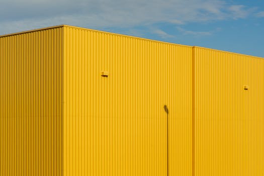Close-up of a bright yellow industrial building with clear sky.