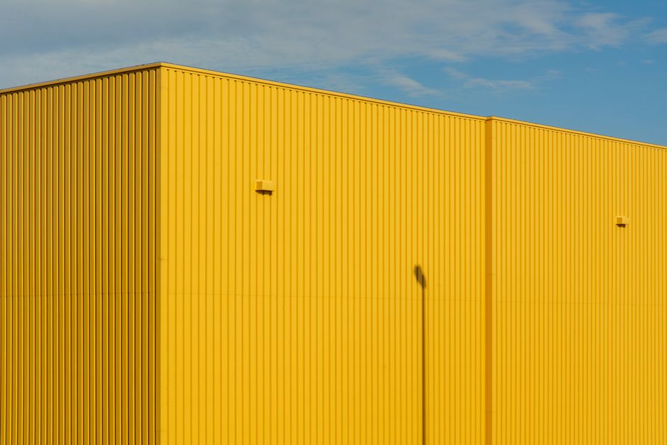 Close-up of a bright yellow industrial building with clear sky.