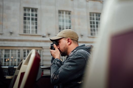 A man taking photos with a camera in an urban setting outdoors.