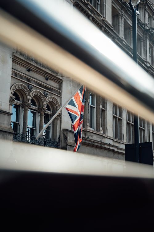 Free Union Jack flag on historic building facade in London, England. Stock Photo