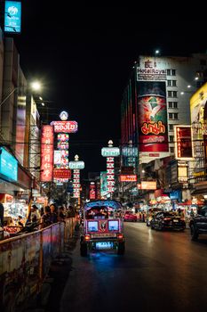 Vibrant night street scene in Bangkok's Chinatown featuring colorful neon signs and bustling activity.