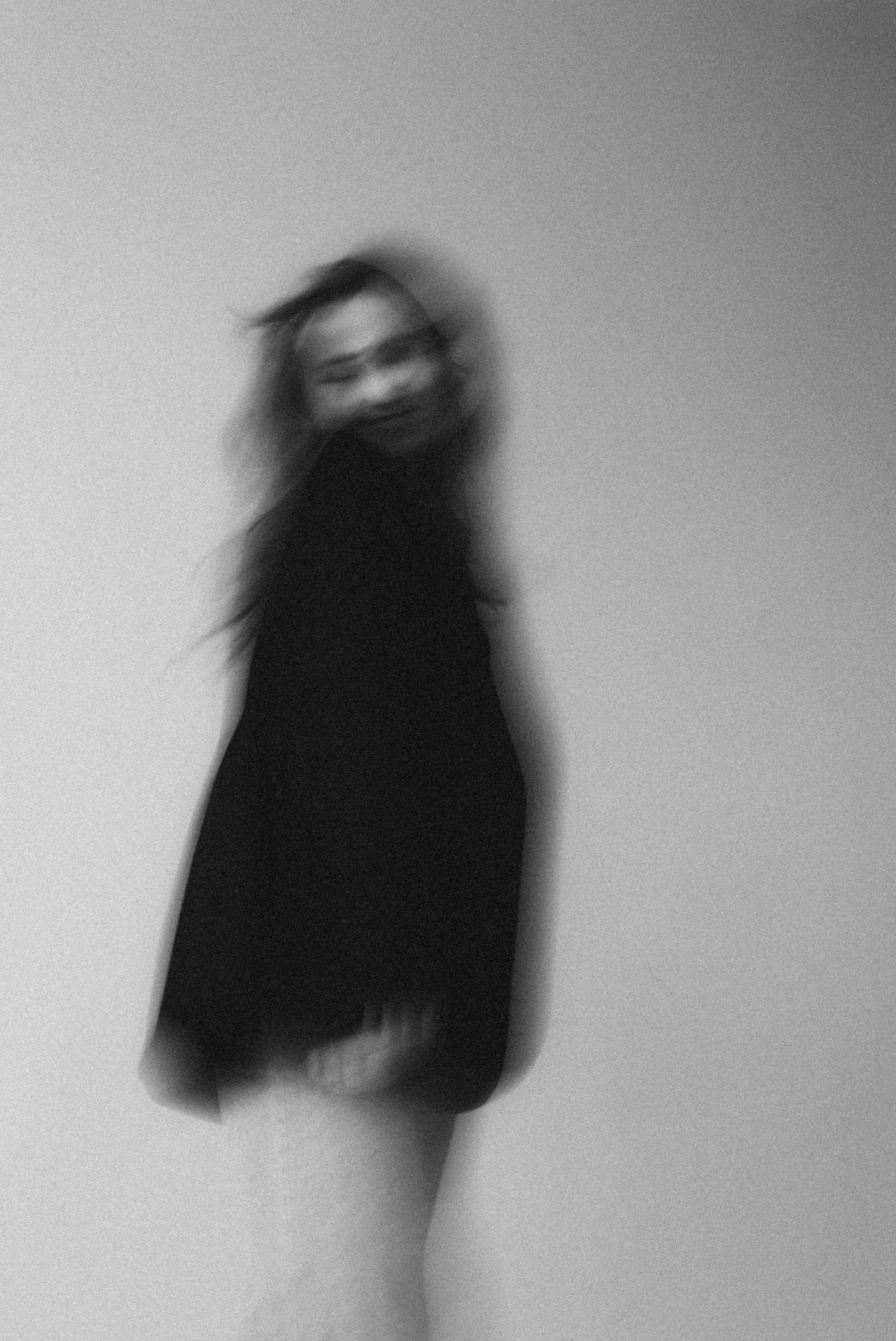 Black and white blurred portrait of a woman in motion, creating an artistic and mysterious effect.