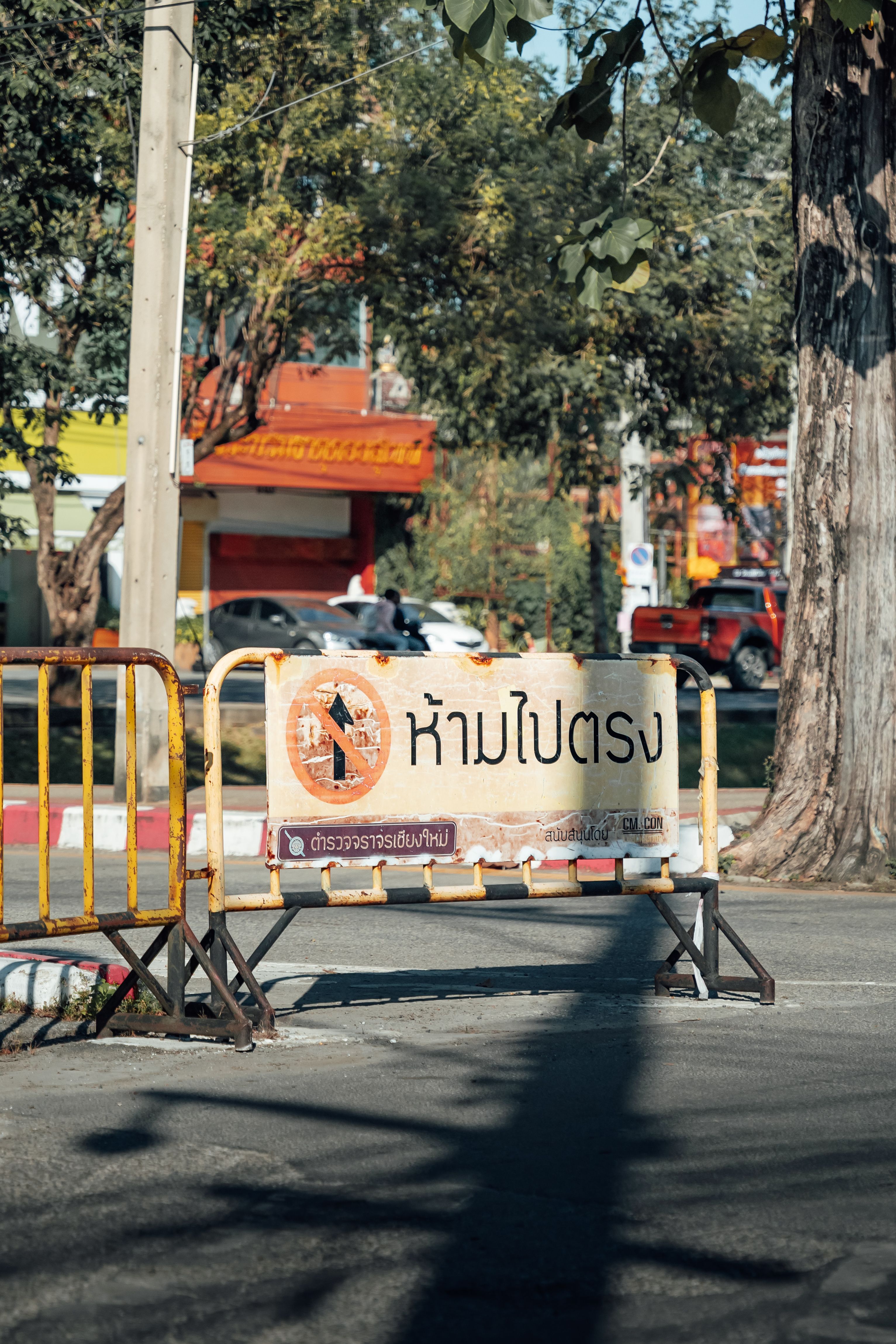 A traffic barrier with a sign in Thai language on a sunny street in Chiang Mai, Thailand.
