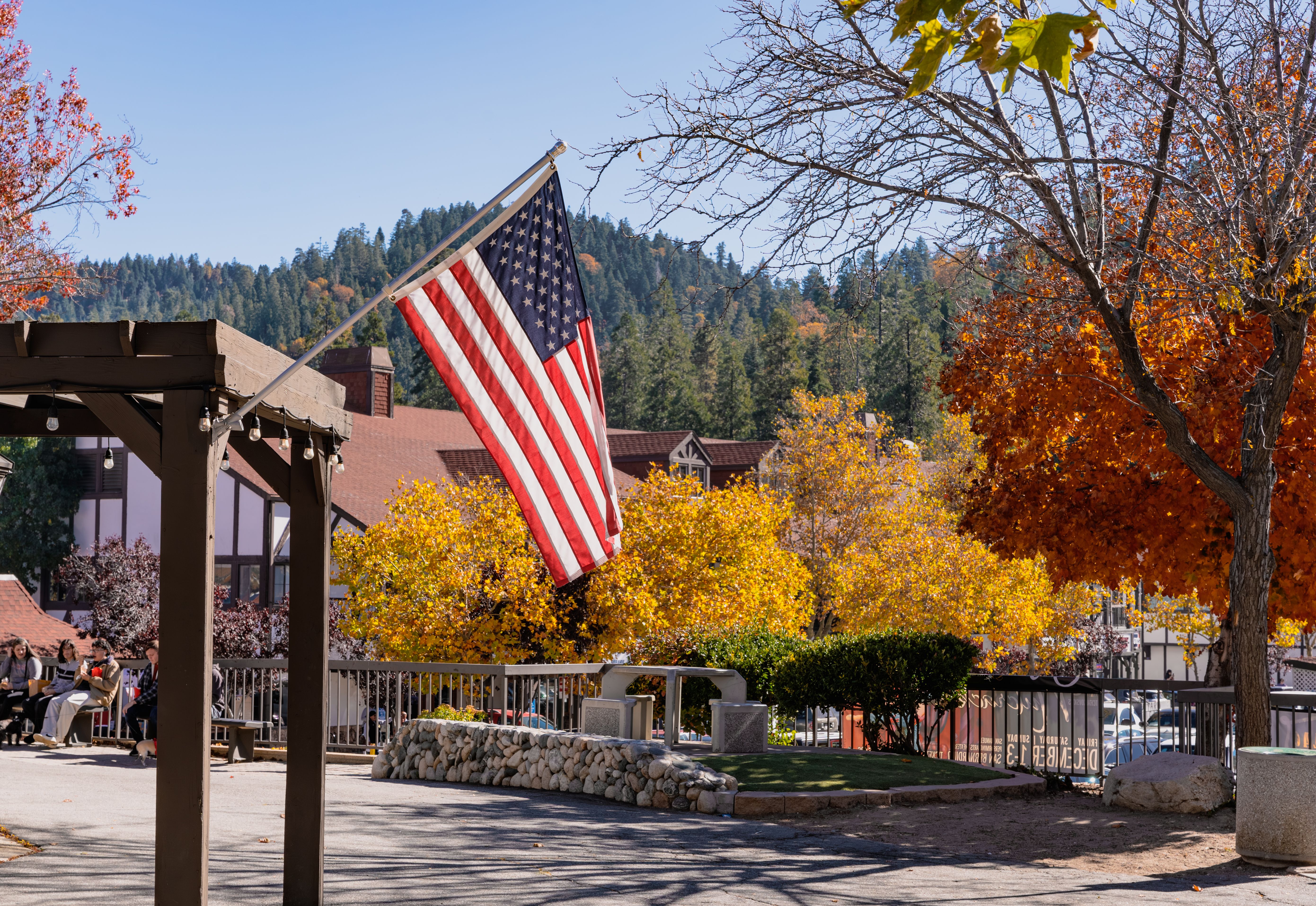 A picturesque fall scene at Lake Arrowhead, California with vibrant foliage and an American flag waving in the breeze.