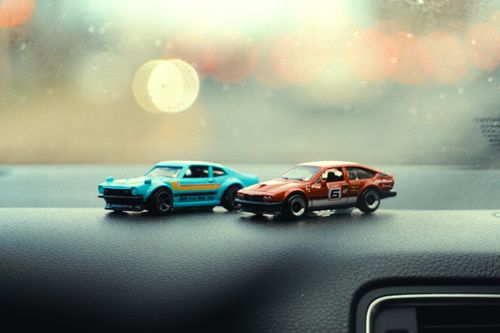 Free Two vintage toy cars on a car dashboard with a bokeh effect in the background. Stock Photo