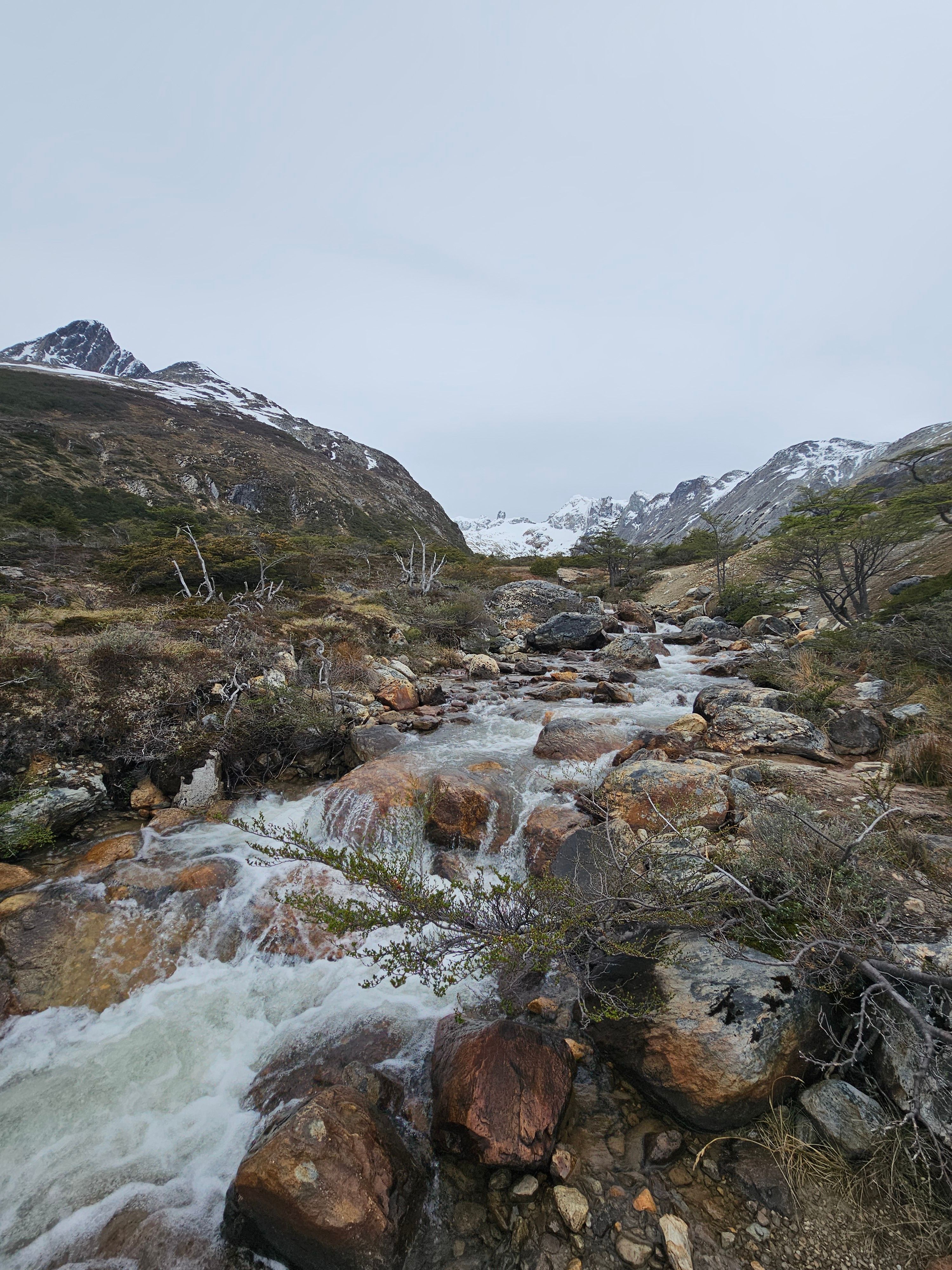 Mountain Stream in Rocky Terrain with Snowcapped Peaks · Free Stock Photo