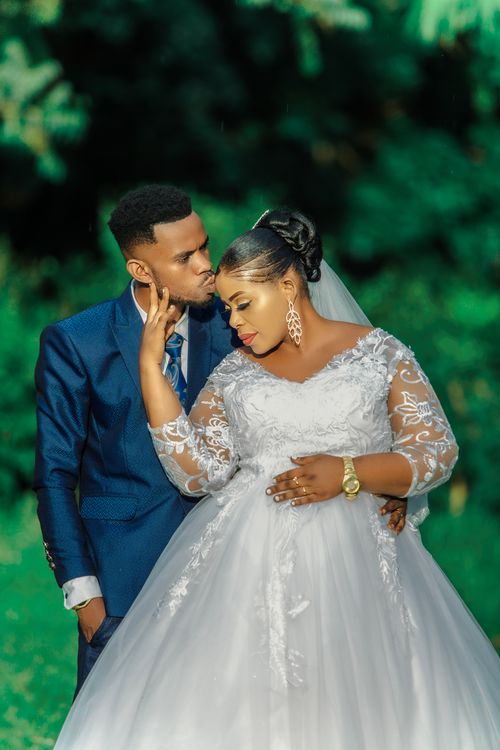 Free A joyful couple shares a tender moment in a lush outdoor setting on their wedding day. Stock Photo