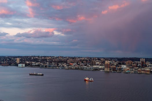Vibrant sunrise over a cityscape with colorful clouds and ships on the water.