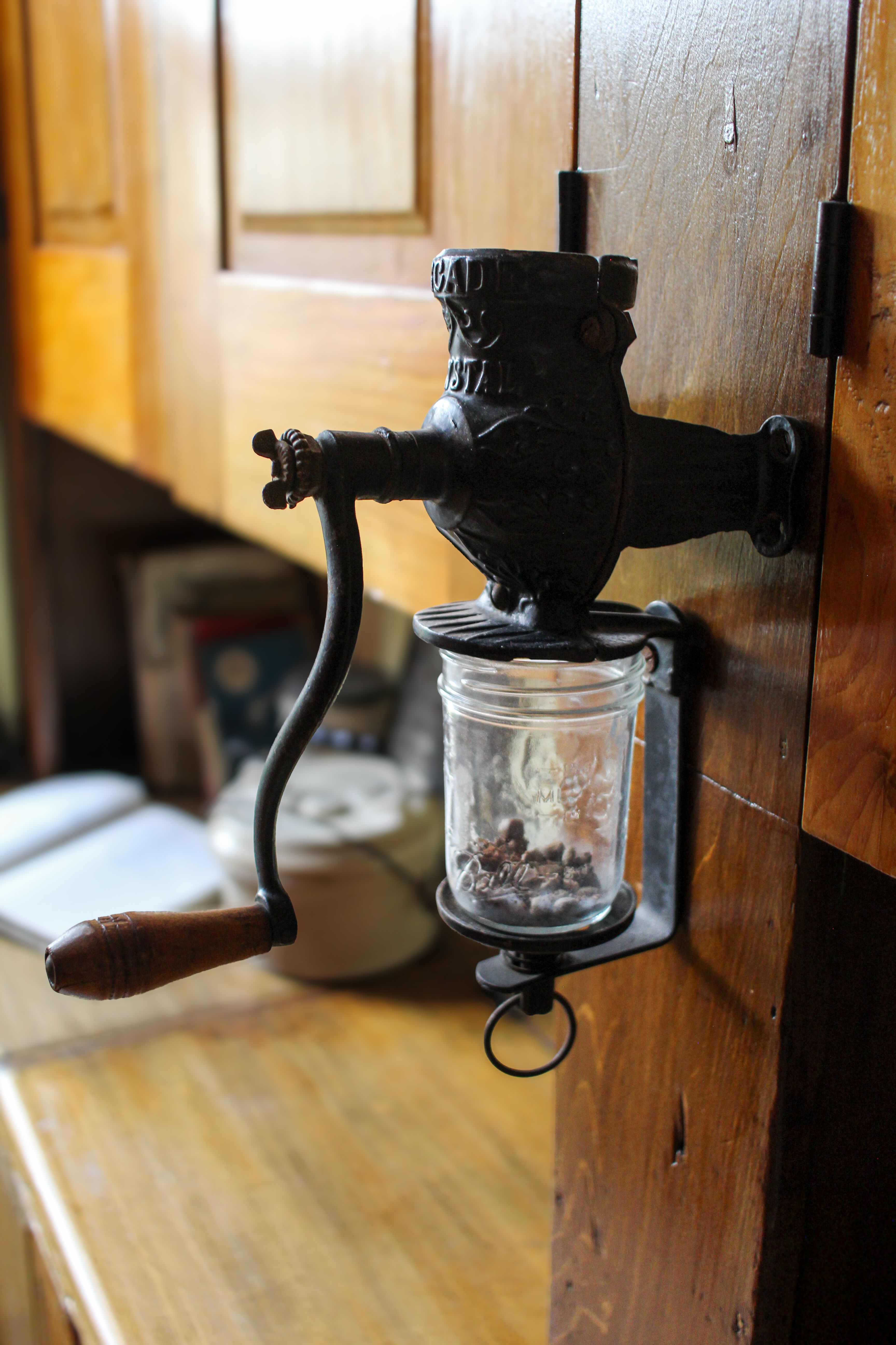 A kitchen coffee cabinet with mounted airtight coffee bean canisters on the inside of the door