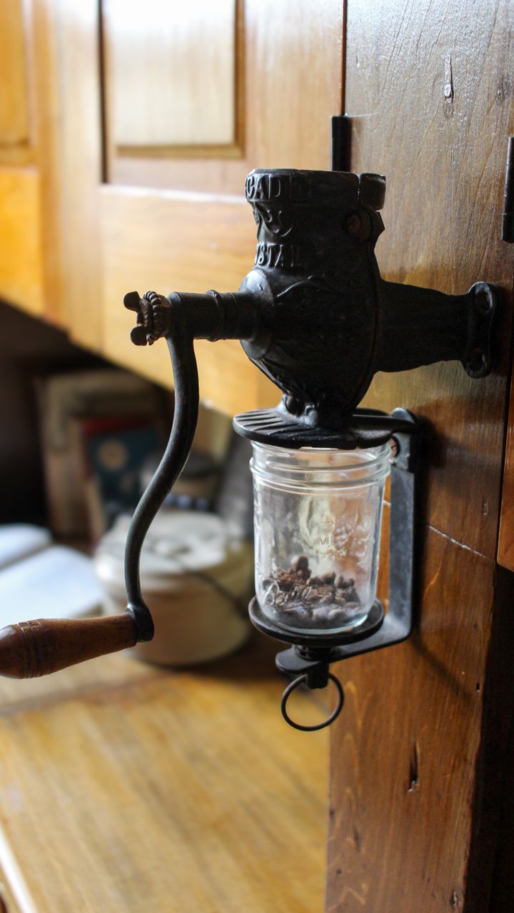A kitchen coffee cabinet with mounted airtight coffee bean canisters on the inside of the door