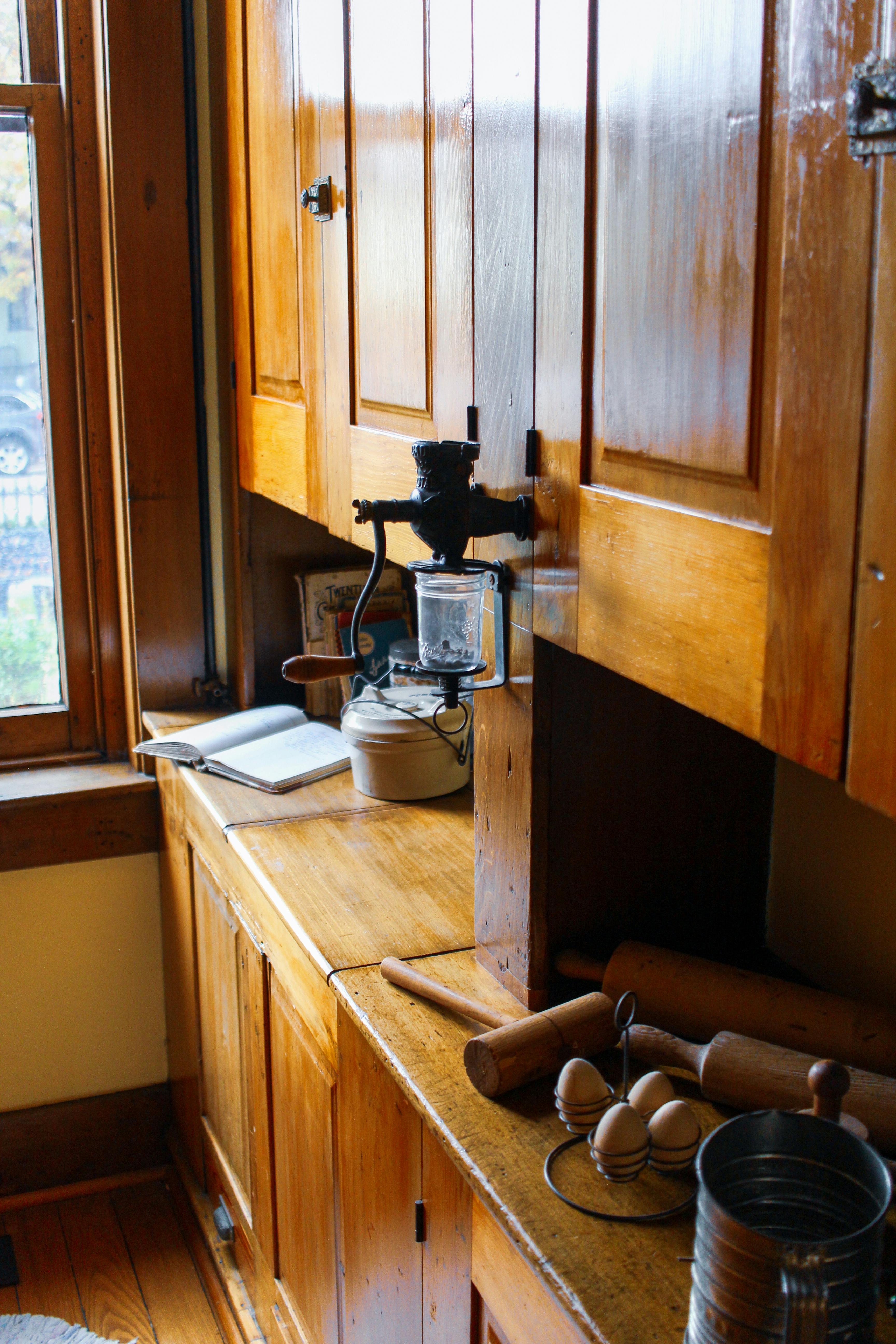 Rustic kitchen setting with wooden cabinets, eggs, and antique grinder.