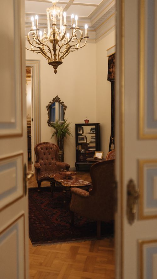 Free A luxurious vintage room with classic furniture, chandelier, and elegant decor visible through a doorway. Stock Photo