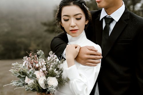 Женщина в белом платье с длинными рукавами рядом с мужчиной