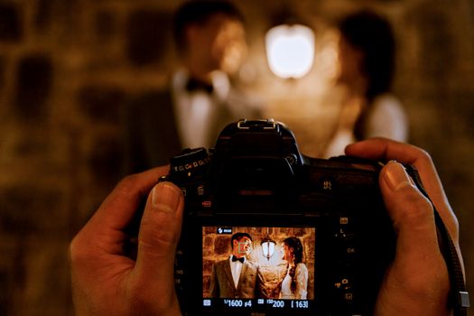 A romantic couple captured through a camera screen with warm lighting indoors.