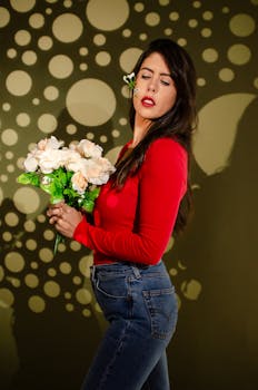 Elegant woman in red holds white flowers against a unique circular pattern background.