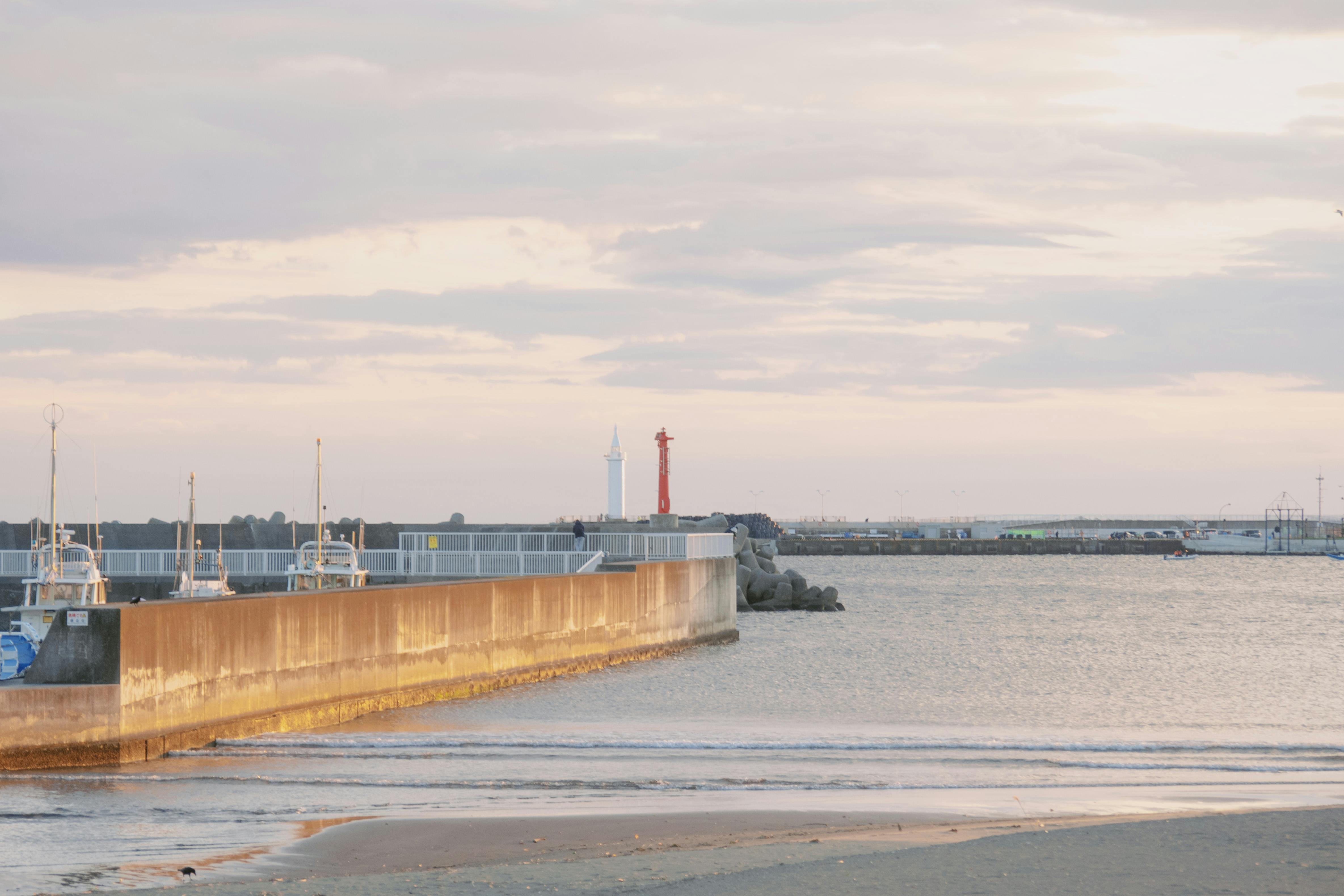 Tranquil seaside view with a pier and lighthouse, perfect for travel and leisure themes.