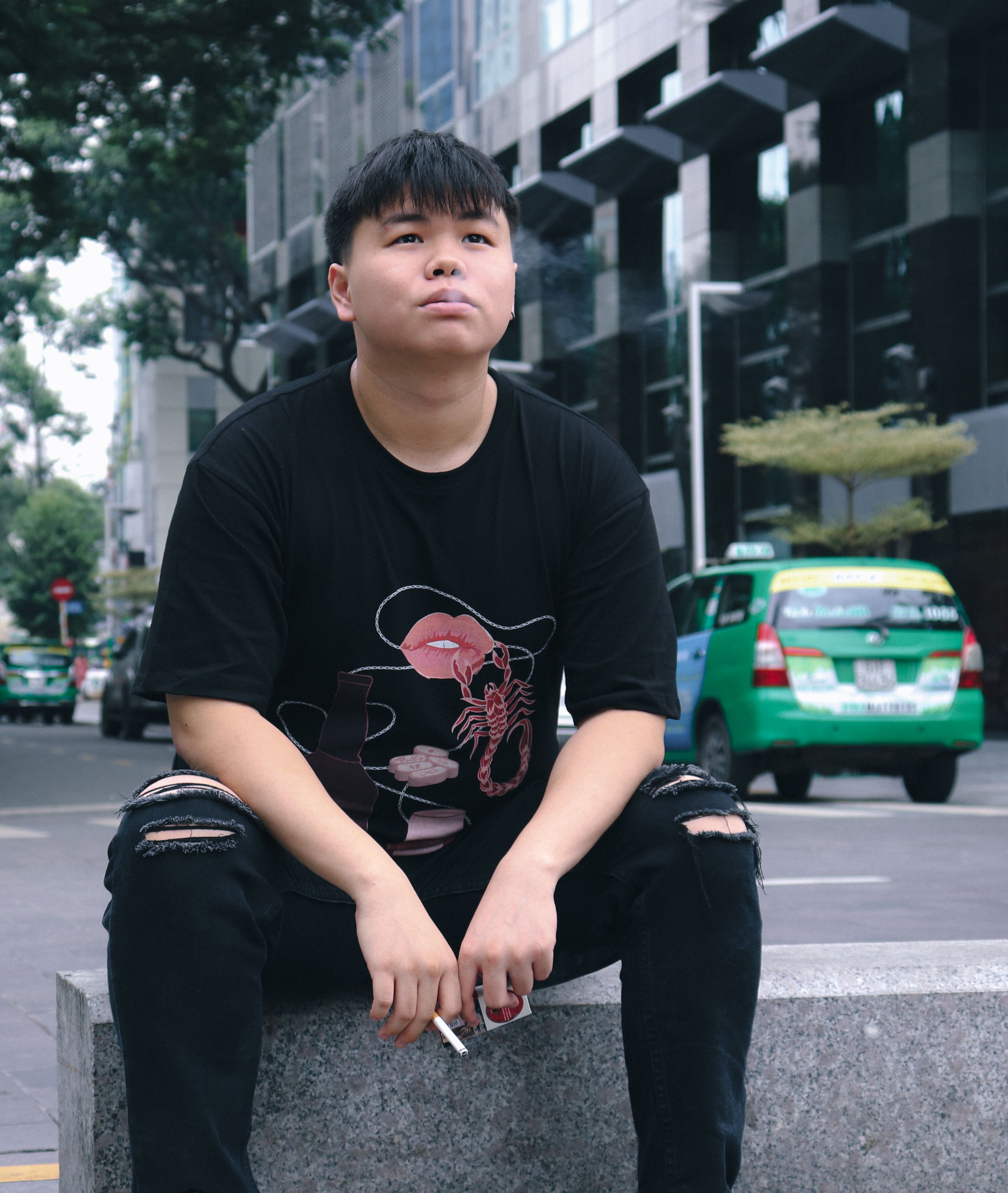 Casual portrait of a young man sitting on a bench in bustling Ho Chi Minh City.