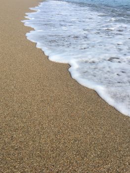 Peaceful ocean waves gently lapping on a sandy Sardinian beach.