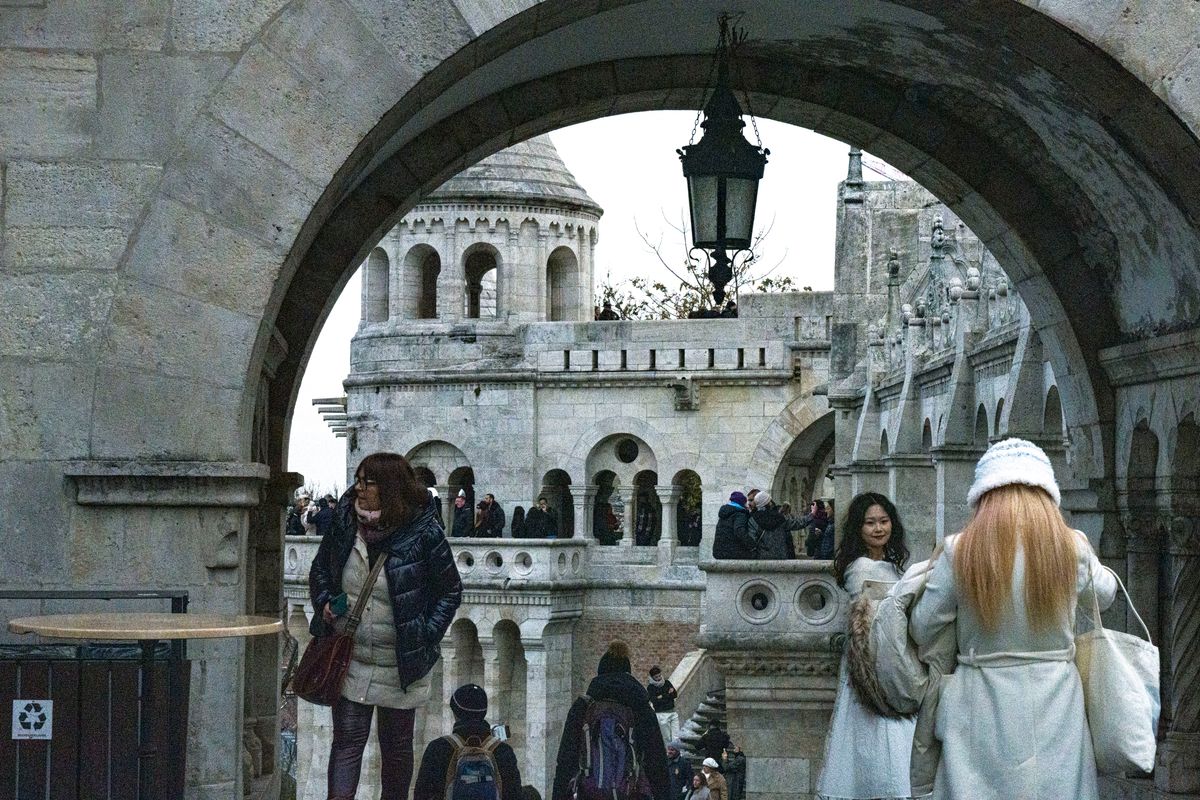 Arcadă de piatră a Bastionului Pescarilor din Budapesta, cu vizitatori în geci groase și căciuli
