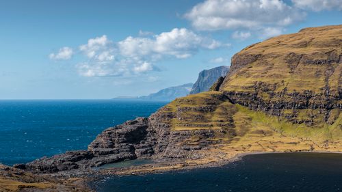 Free A stunning view of mossy cliffs overlooking the Atlantic Ocean under a bright blue sky in the Faroe Islands. Stock Photo