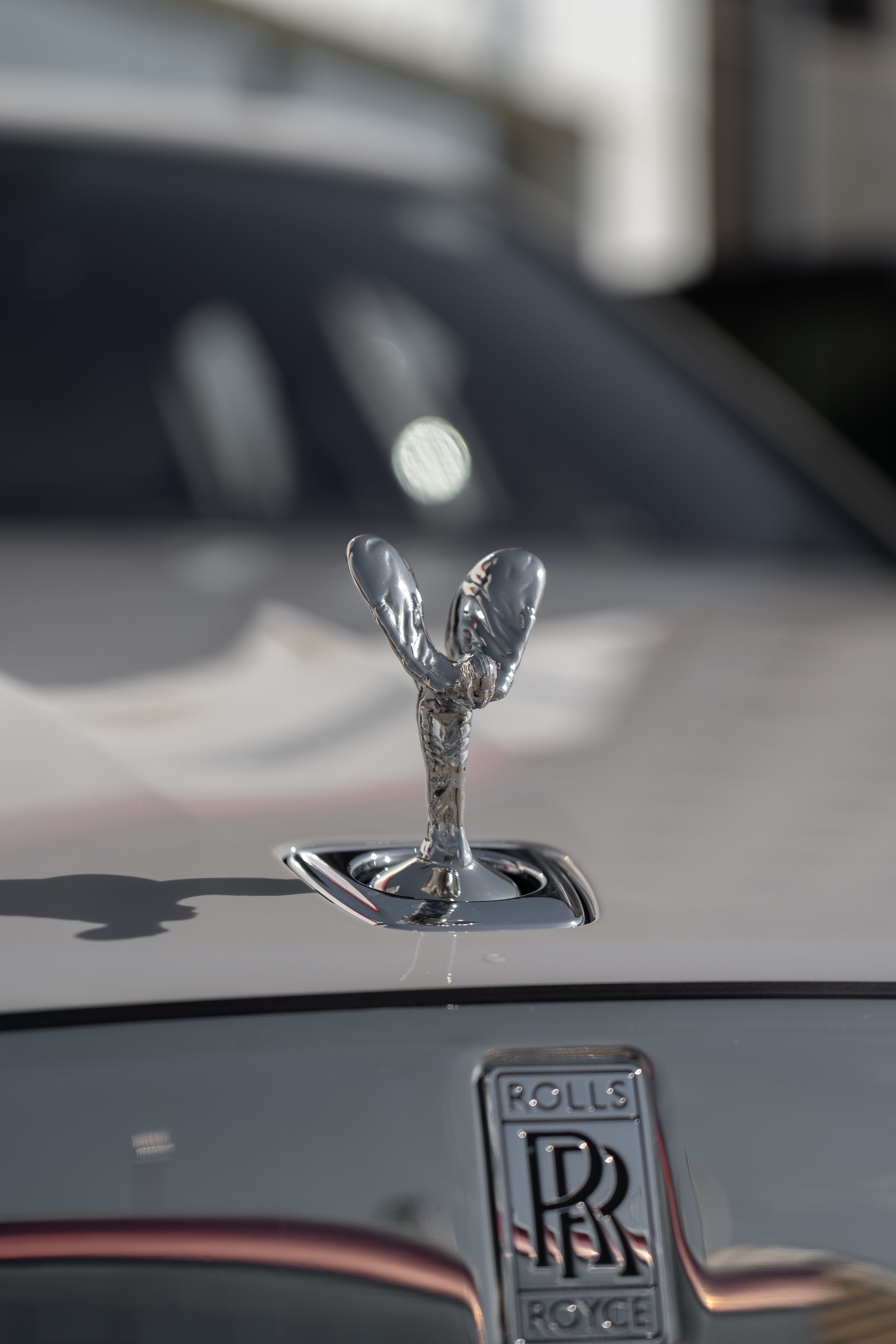 Close-up of the iconic Rolls-Royce Spirit of Ecstasy hood ornament in bright sunlight.