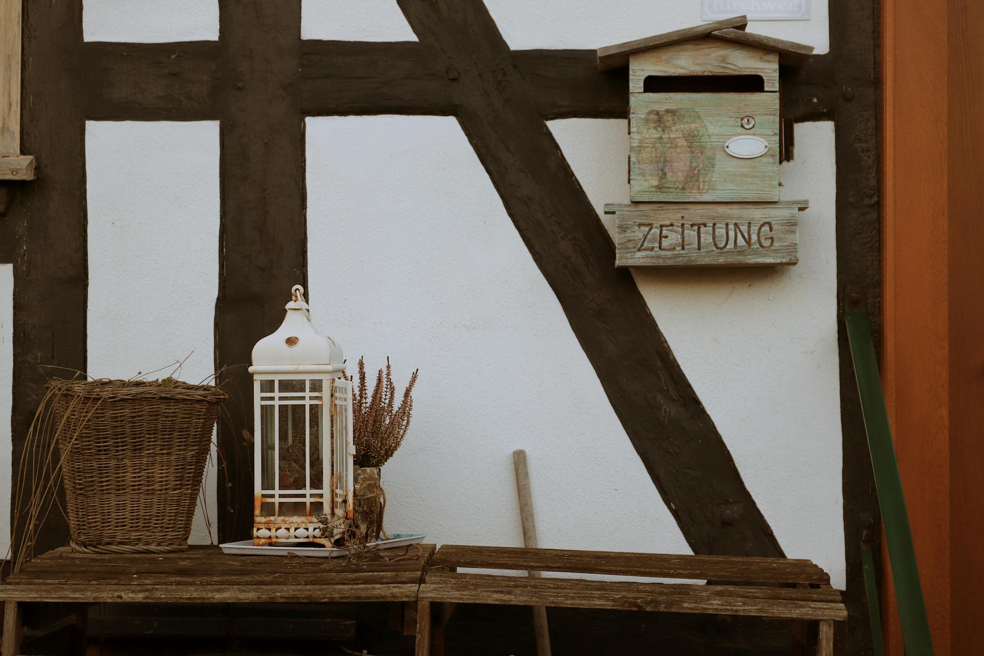 Charming timbered house entrance with a basket, lantern, and mailbox in Bad Sooden-Allendorf, Germany.