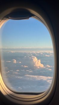 Peaceful cloudscape view from an airplane window at sunrise, offering a serene travel moment.
