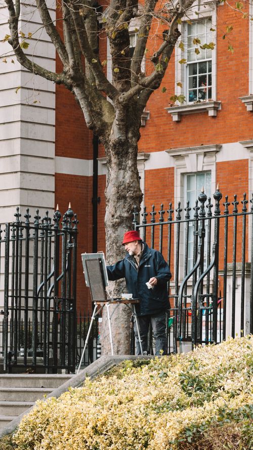 Free Artist painting outdoors by cityscape on a fall day, capturing urban life. Stock Photo