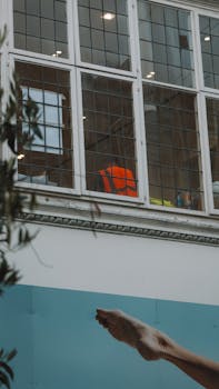 Creative urban scene with a leg against a building and window view.