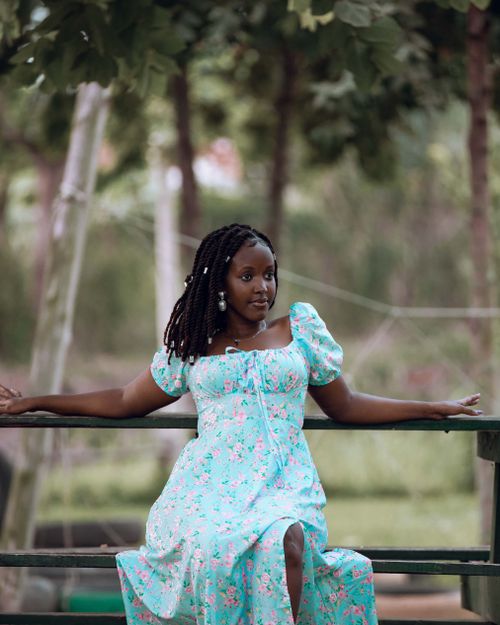 Free Young woman in floral dress sitting outdoors, enjoying nature in a serene setting. Stock Photo