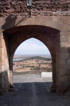 Ancient stone archway in a Portuguese castle offers a sweeping view of the landscape.