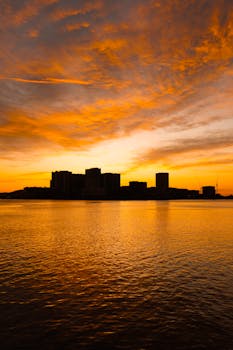 Experience the stunning silhouette of Sydney's skyline against a vibrant sunset over the harbor.