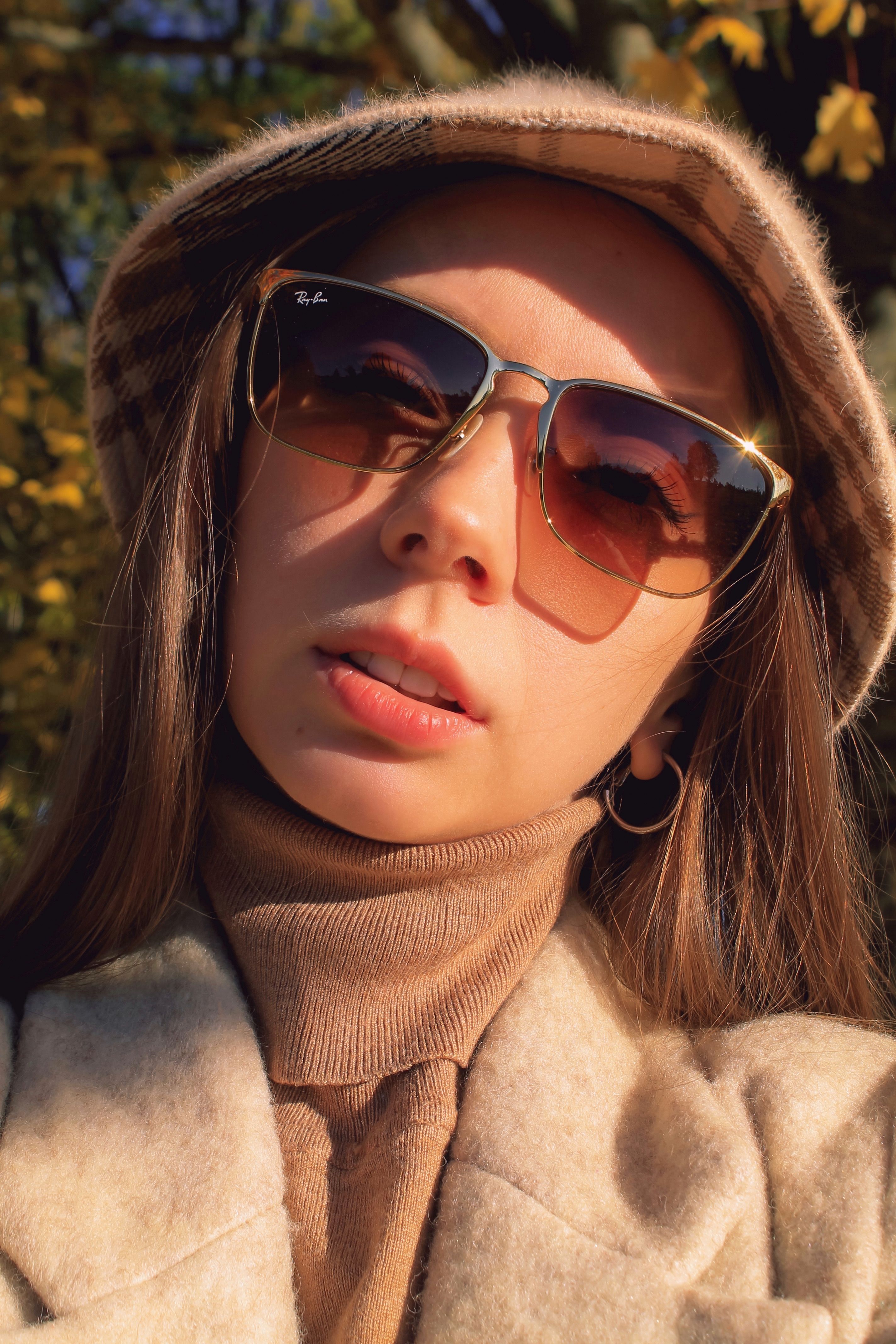 Stylish woman in sunglasses and hat enjoying sunny autumn day.