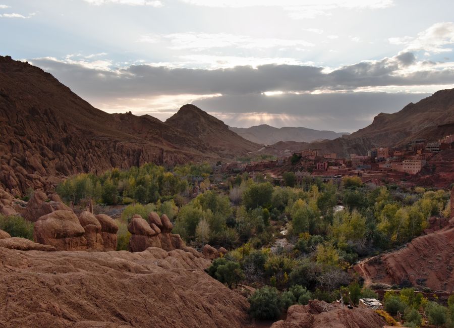 Beautiful valley in Morocco with lush greenery and rocky mountains under a twilight sky.