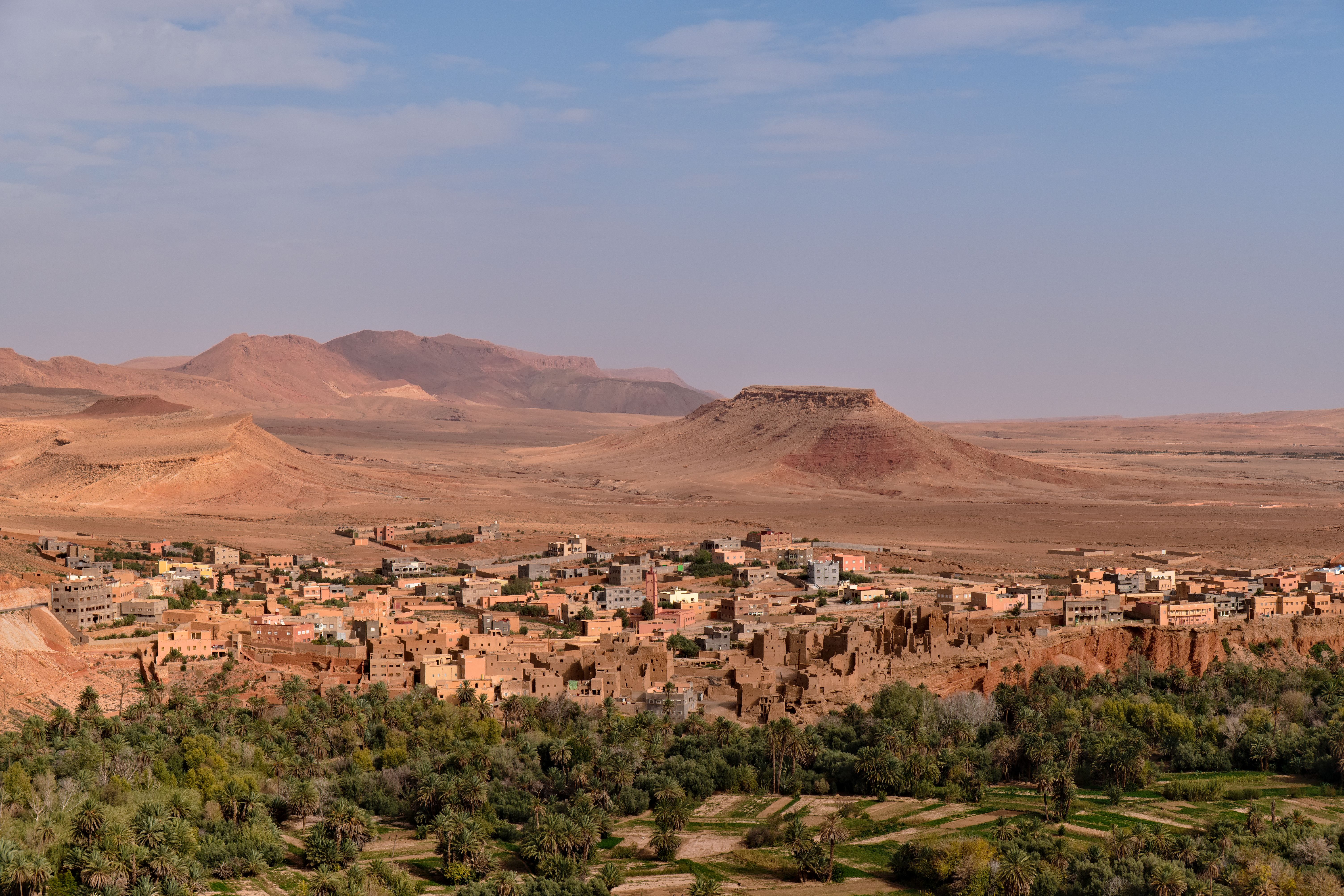 Aerial view of a traditional Moroccan town in a desert landscape with mountains.