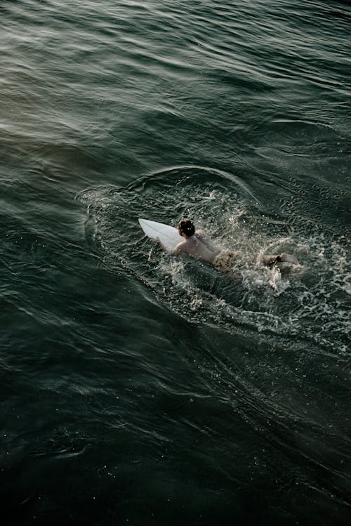 Man Riding White Surfboard on Body of Water