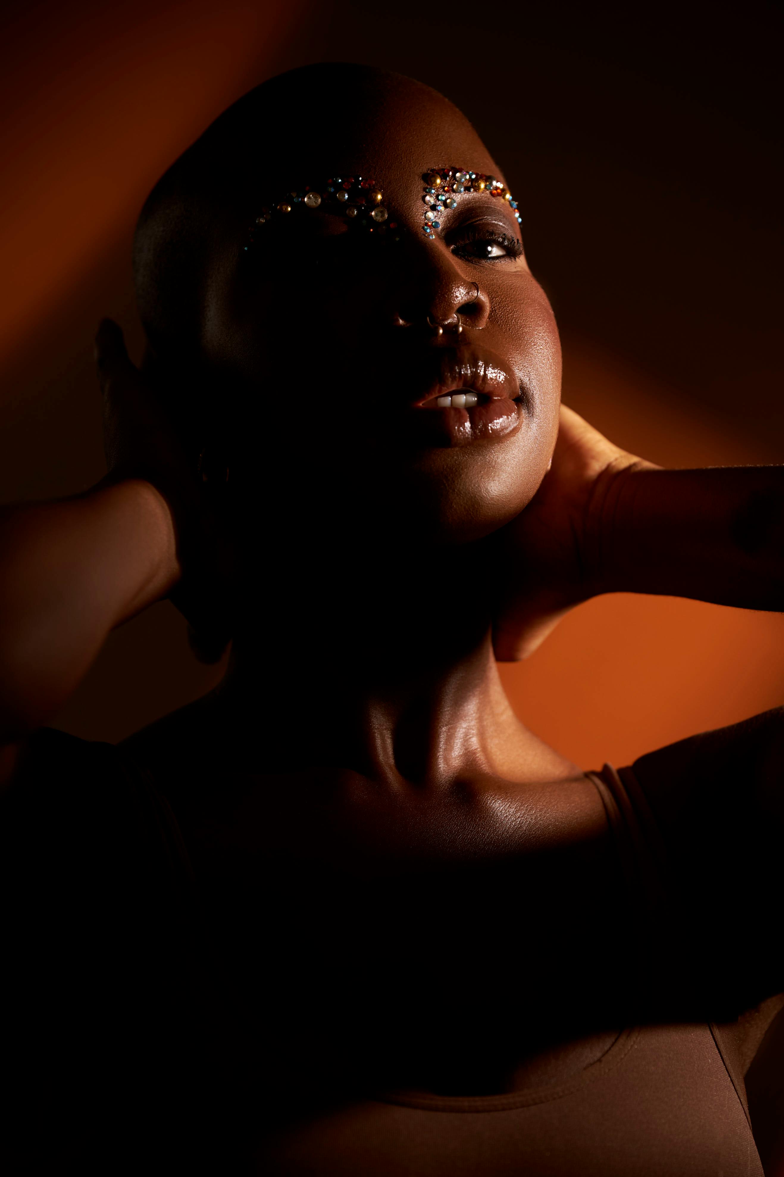 Captivating portrait featuring artistic makeup and dramatic lighting with warm tones.